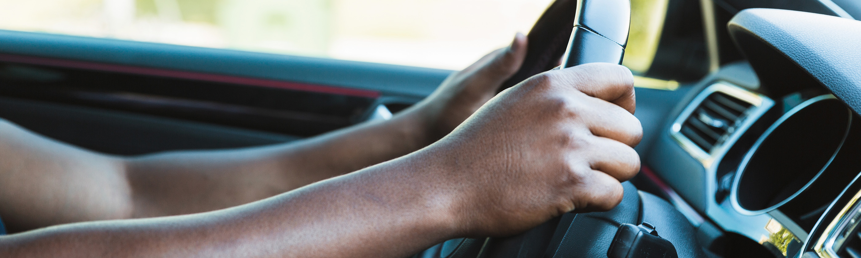 A man grips the steering wheel of his car while driving.